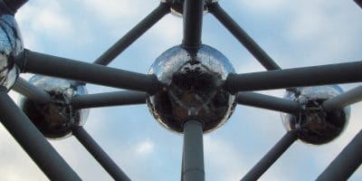 Close-up view of the Atomium structure in Brussels, showcasing its interconnected spheres and steel beams against a cloudy sky.