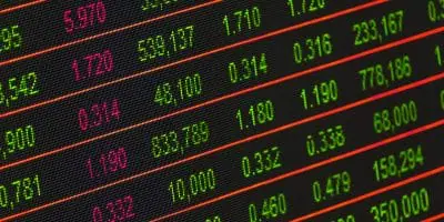 Close-up of a digital screen displaying stock market data with numbers in green and red, representing financial trading and market trends.