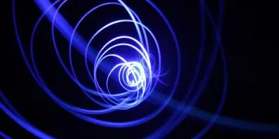 Abstract image of a spiral pattern made of blue light trails against a dark background.