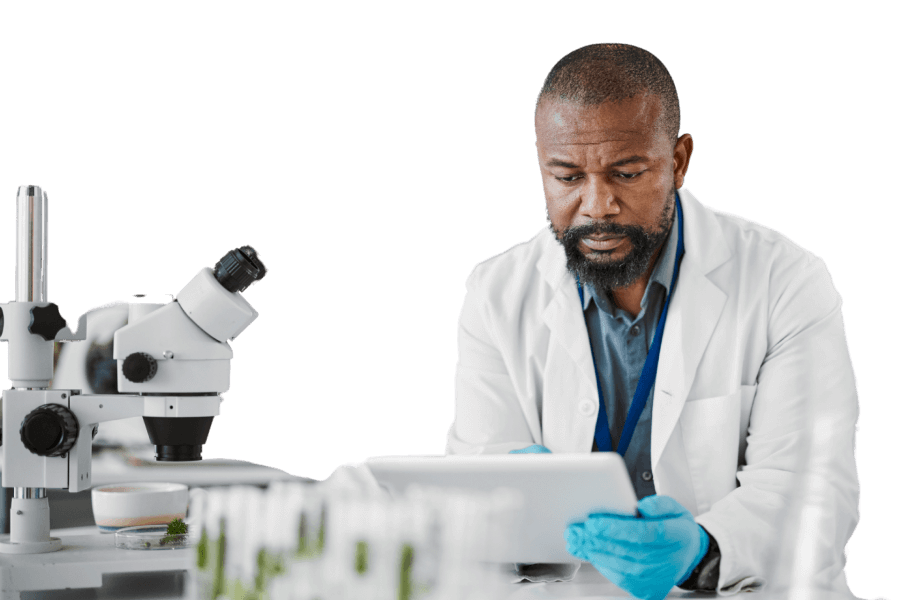 Scientist in a lab coat using a tablet next to a microscope in a laboratory.