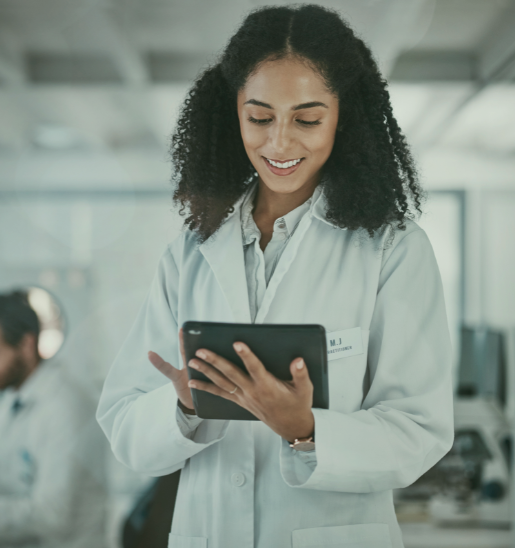 Smiling female scientist with curly hair using a tablet in a lab setting