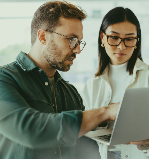 A man and a woman reviewing data on a laptop together in a modern office.